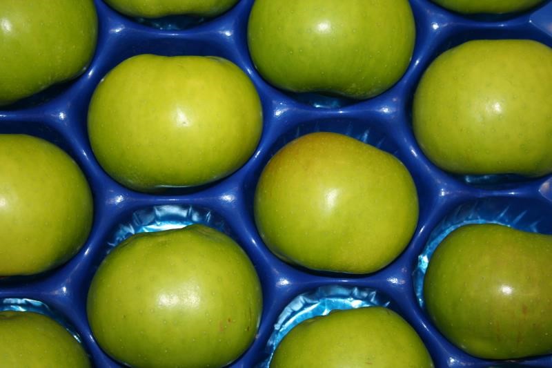 An image showing green apples in plastic tray 