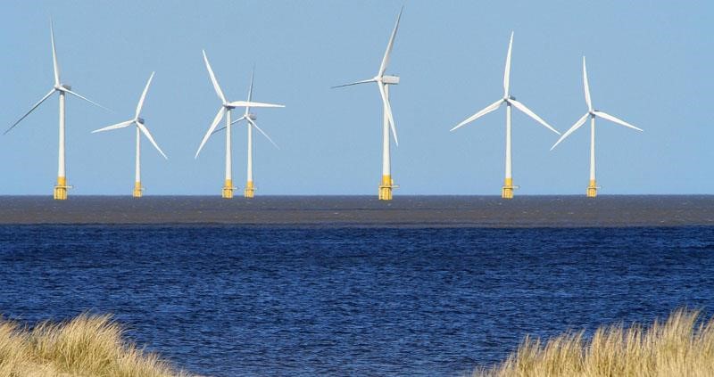 A picture of a row of wind turbines on the shore line