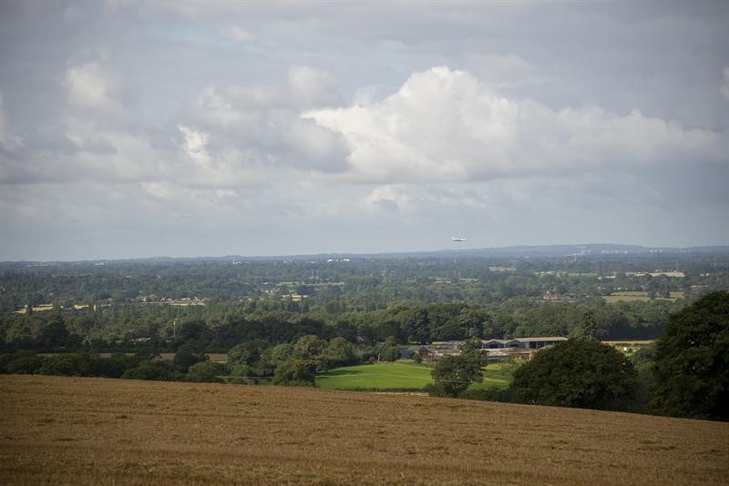 A view of faming landscape, fields, trees and farm buildings. 