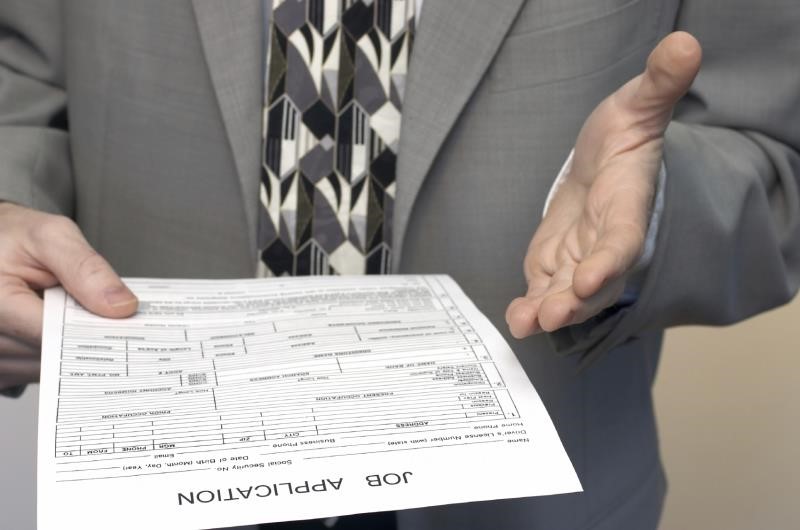 A person in a suit holding a piece of paper that says job application