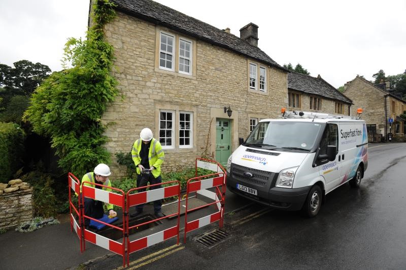 An image showing a BT Openreach van and workmen installing equipment under the pavement outside a cottage