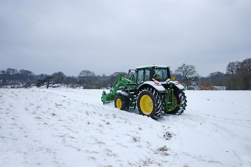 A green tractor in the snow