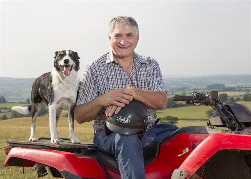 Thomas Binns sitting on his quad bike with his sheep dog and his safety helmet on his lap