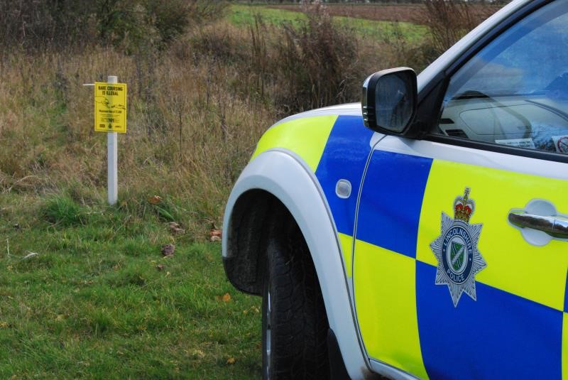 A police car by a hare coursing sign