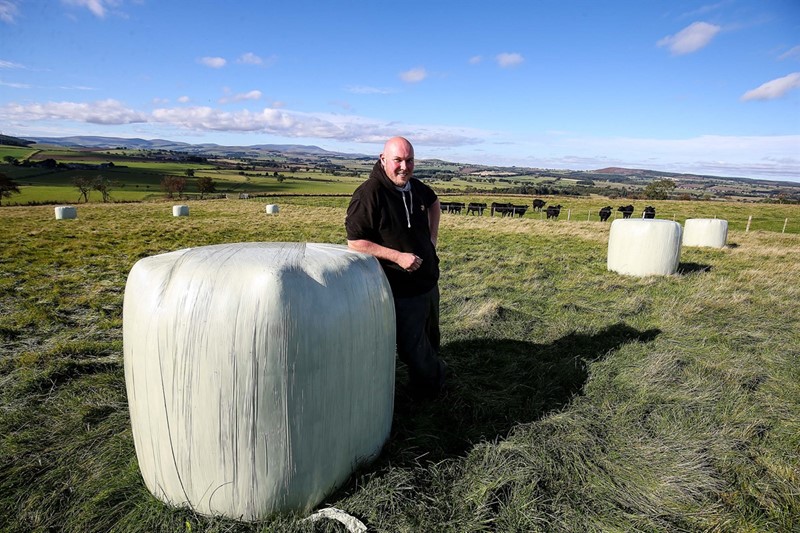 James Drummond on farm 2021 with silage bales_82394
