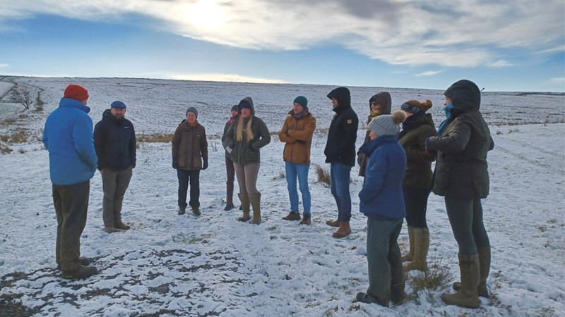 A group of farmers and NFU staff standing in a snowy hill landscape with the Defra landscape team