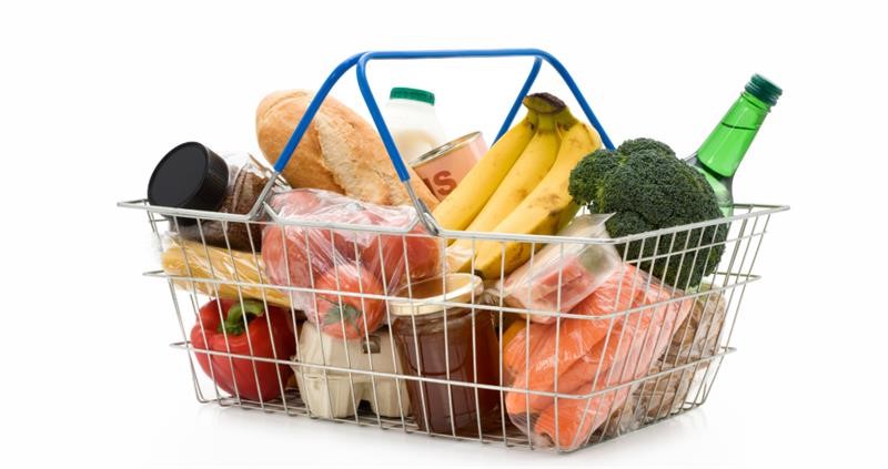 A shopping basket with carrots, bacon, jam, peppers, eggs, bread, milk, tomatoes