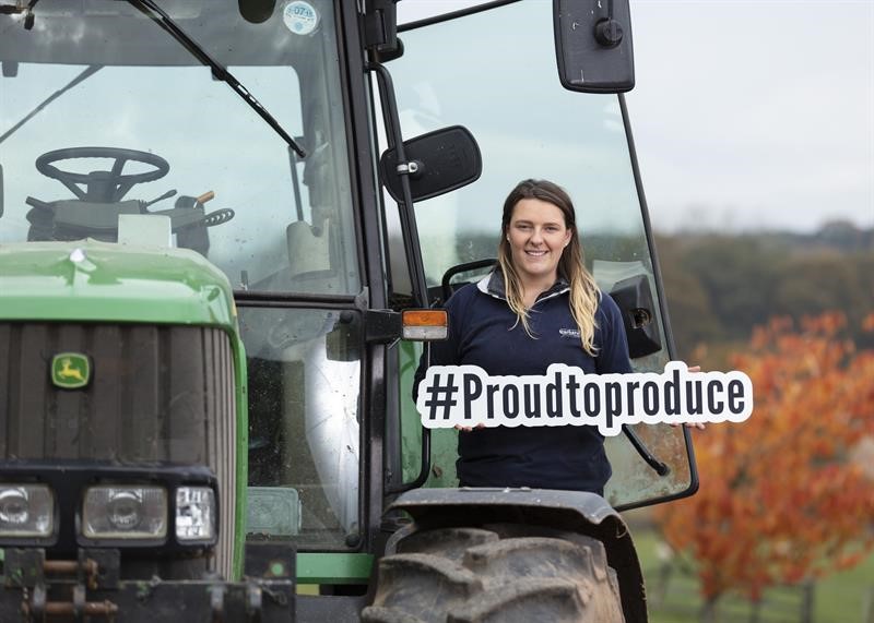 Image of a farmer with a proud to produce sign 