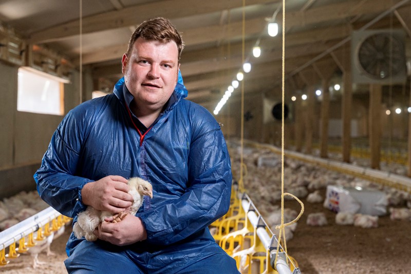 NFU poultry board chair James Mottershead in his poultry shed kneeling down holding a chicken