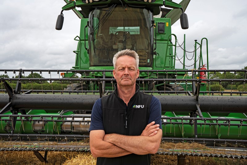 NFU Deputy President David Exwood standing with his arms crossed in front of a combine harvester.