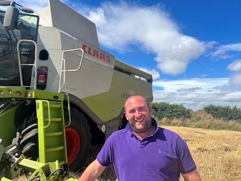 Farmer Jamie Burrows in front of a combine harvester