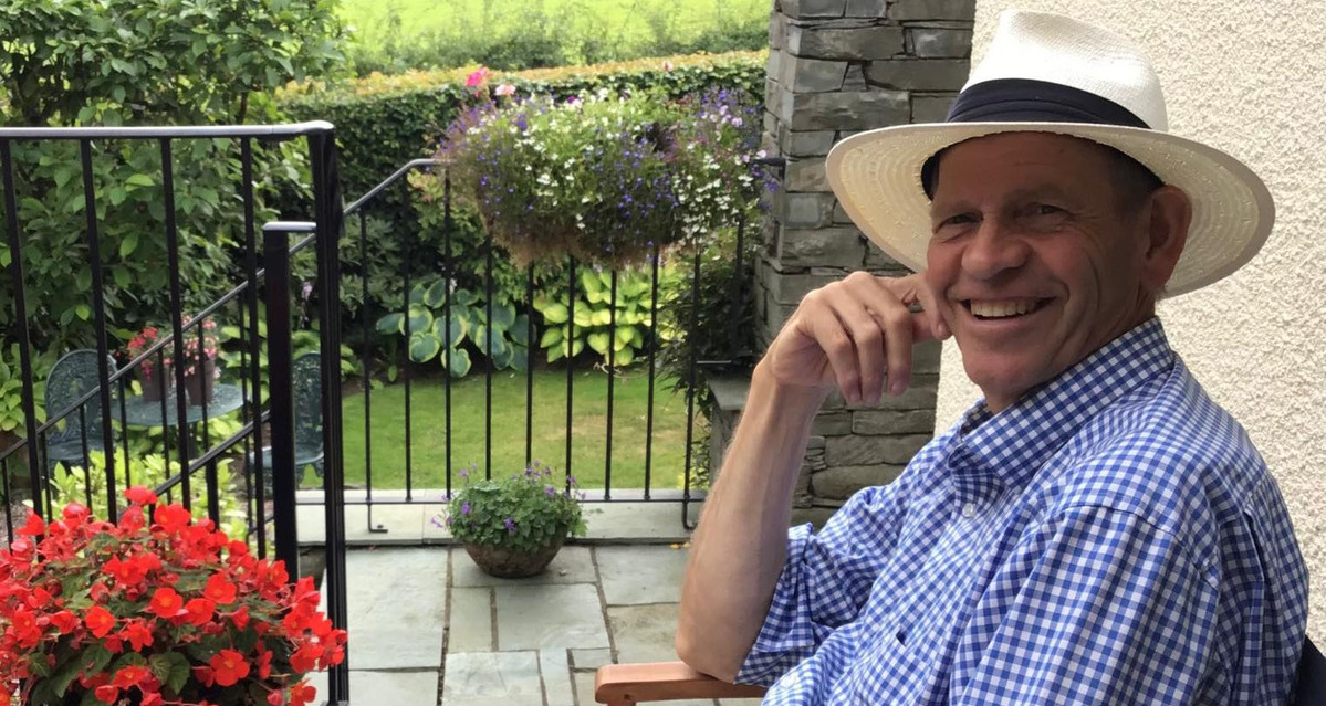 A photo of Nick Utting smiling at the camera sat on a chair in a garden