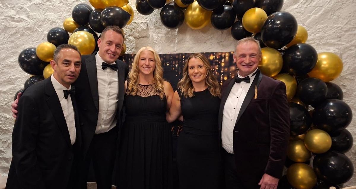 A group photo of guests at the Harvest Ball smiling at the camera in front of a balloon display