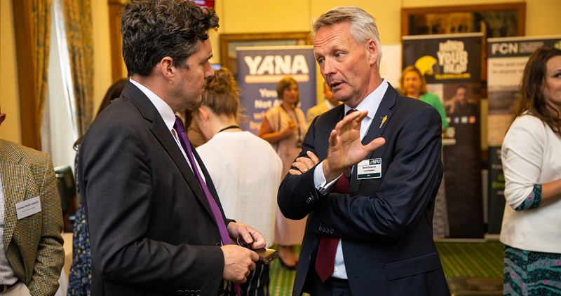 An image of Huw Merriman and David Exwood standing and talking seriously at official reception