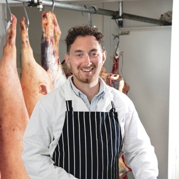 Ed Harrison poses for a photo behind his butcher's block