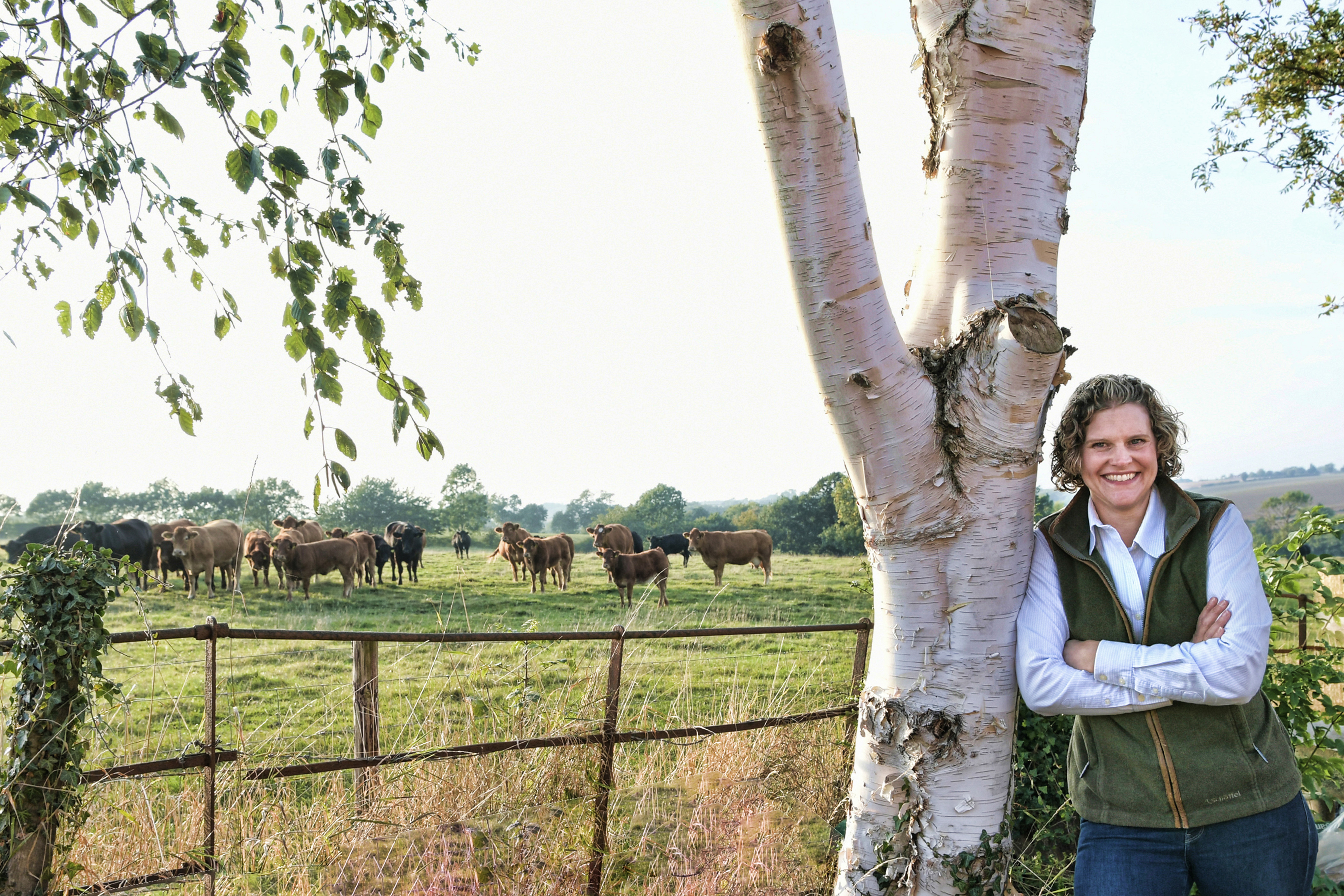 An image of NFU Crops Board member Sarah Bell taken on her farm with cattle in the field behind her.