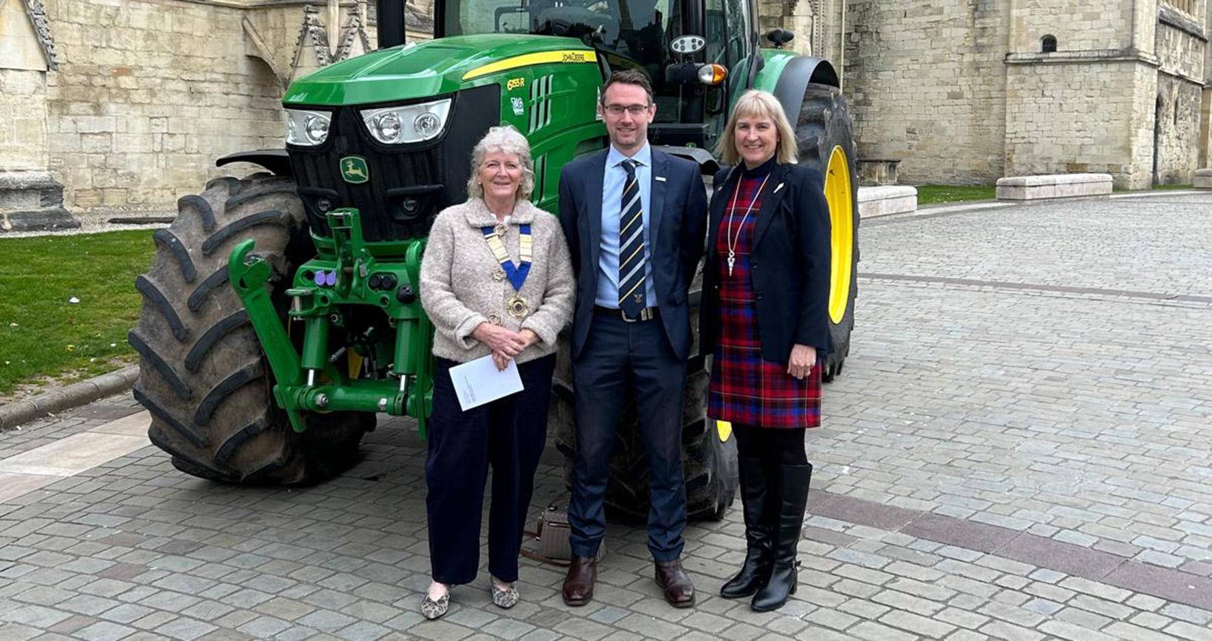 Three people standing in front of a tractor