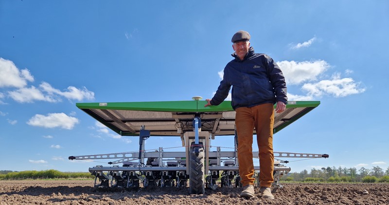 An image of Richard stood in front of machinery on his farm