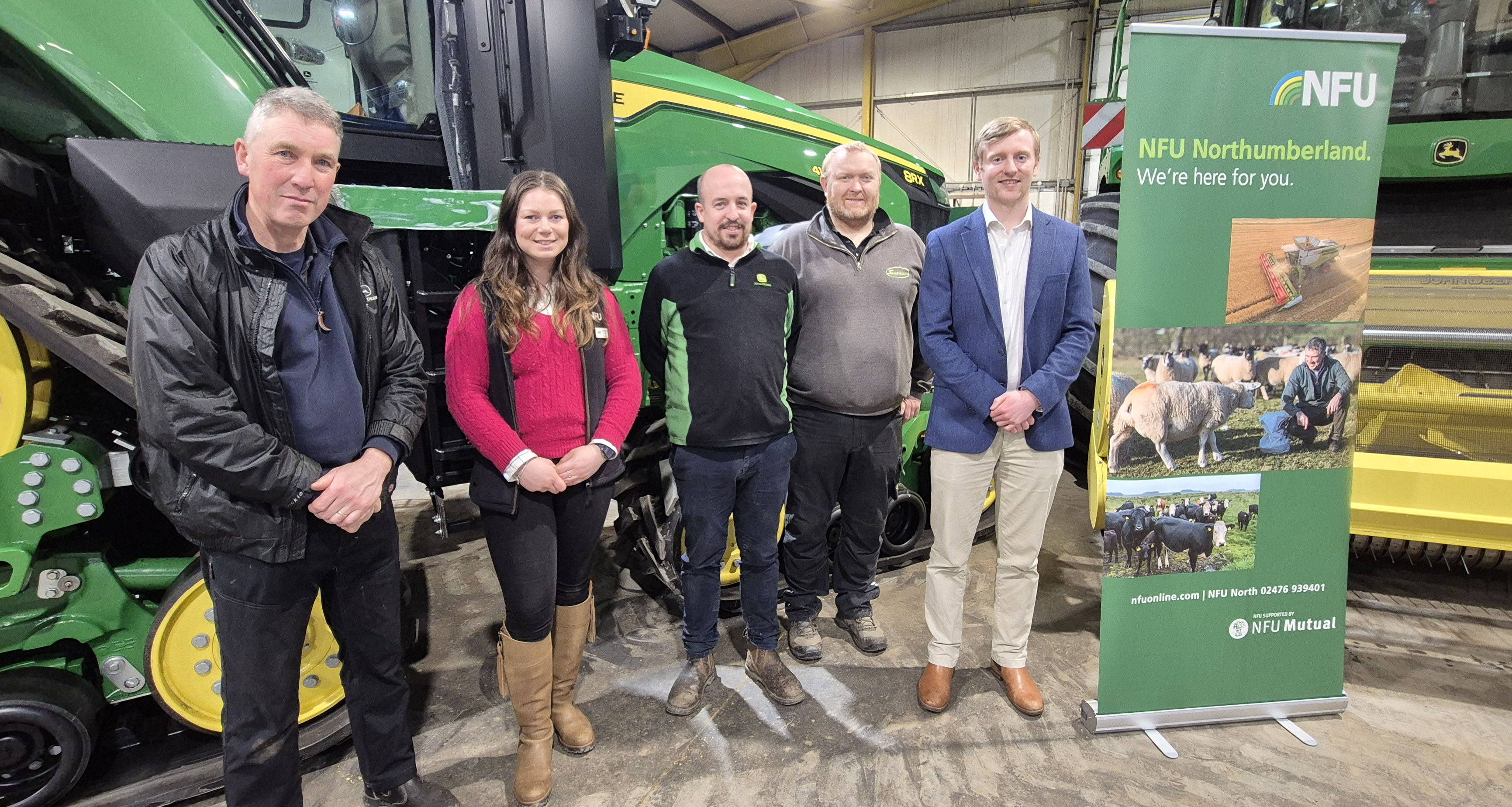 Mac Young, Charlotte Dring, Thomas Sherriff staff and Stuart Head stood next to an NFU banner in front of machinery