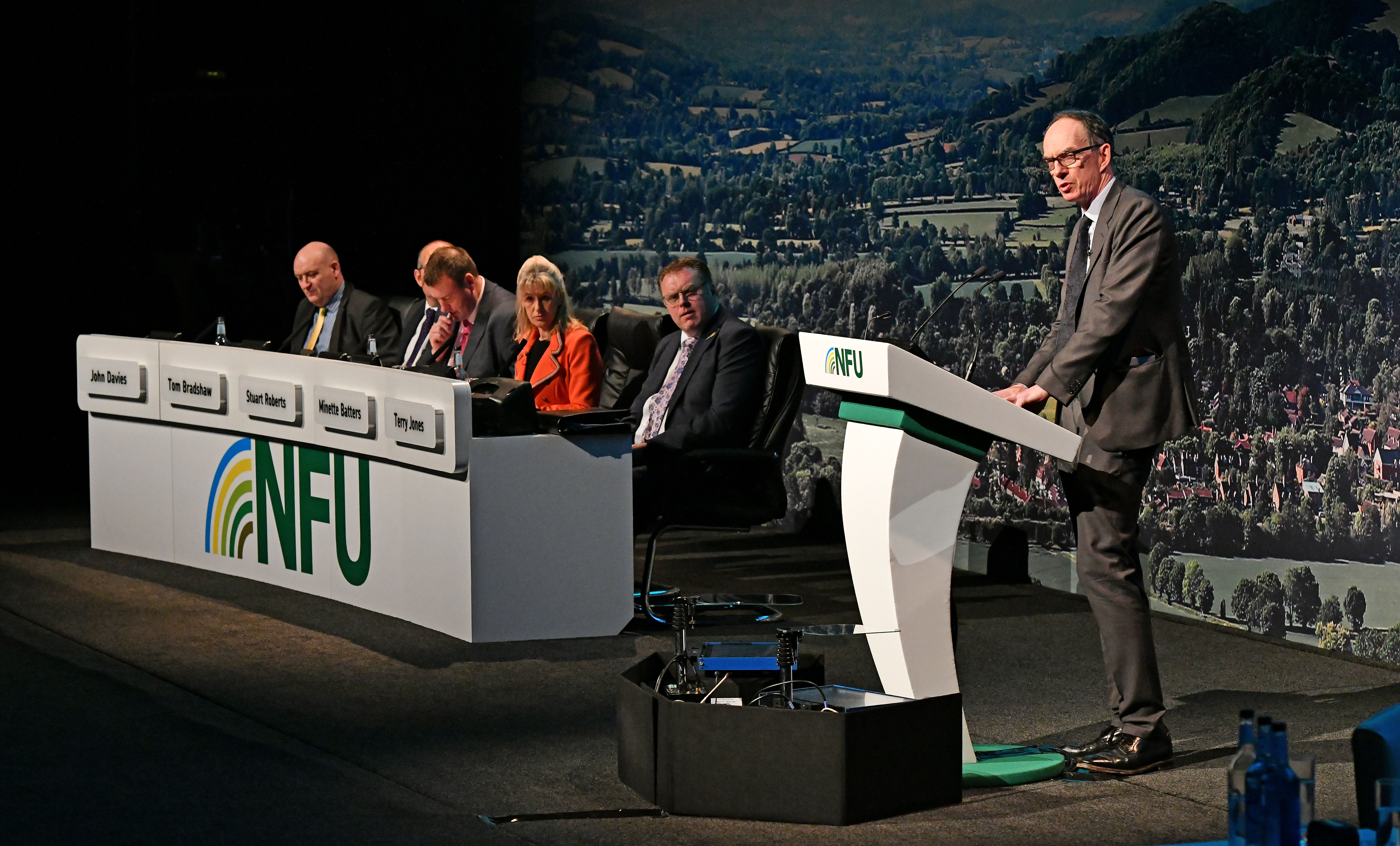 A picture of Sir David Ramsden CBE, Deputy Governor for Markets & Banking at the Bank of England, speaking at the stand at NFU Conference 2022, with the panel of speakers in the background.