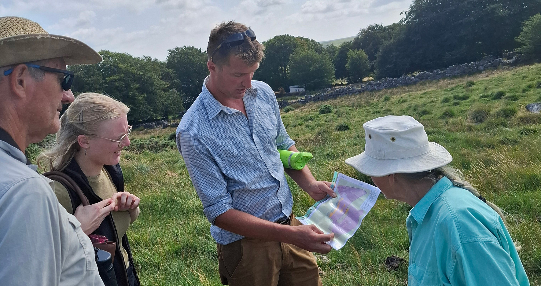 A group of people in a field looking at a map