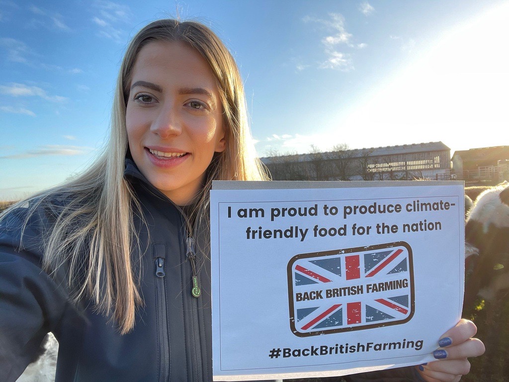 Josie Troop with I am proud to produce climate friendly farming sign