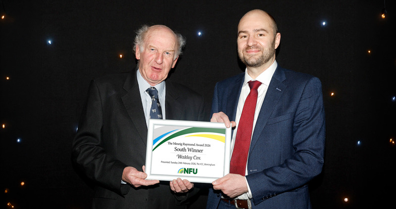 Two men standing in front of a starry backdrop holding a framed certificate