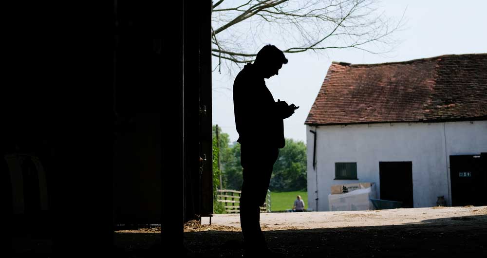 Duncan Hawley's silhouette agains the backdrop of barn and farmhouse