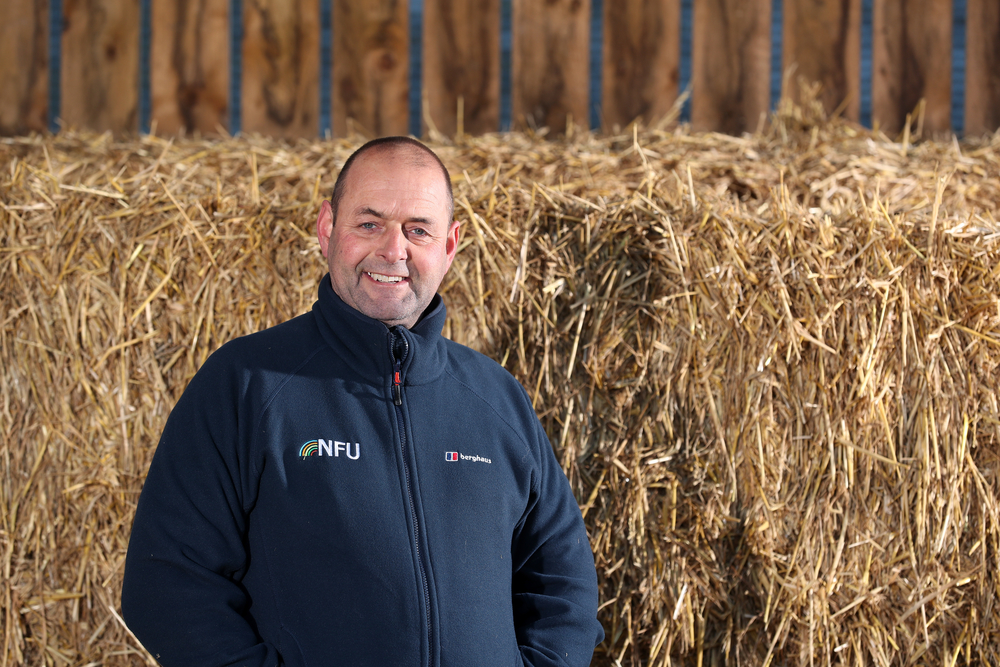 Michael Oakes smiling in front of hay stacks
