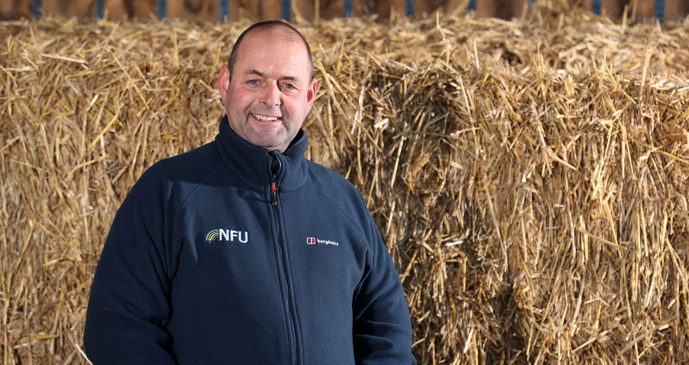 Michael Oakes smiling in front of hay stacks