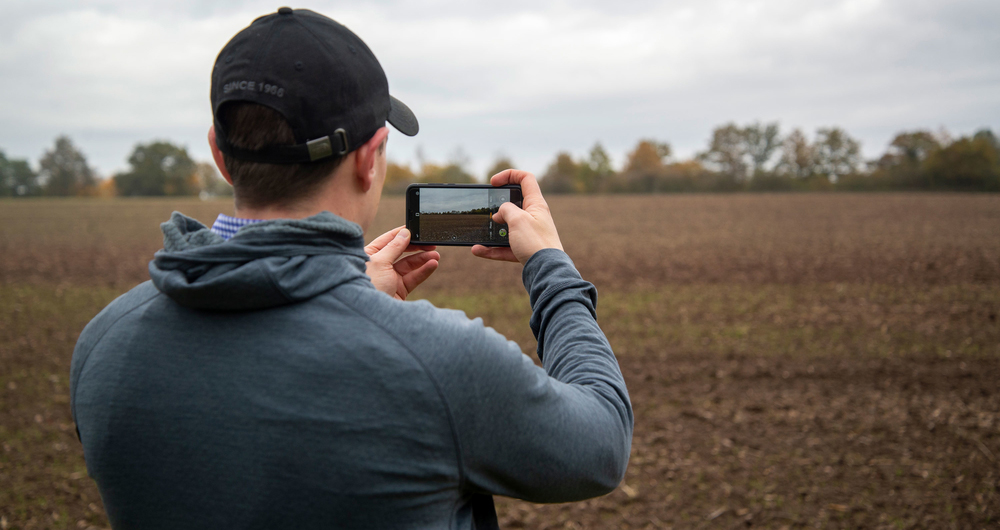 A person standing in a field with a mobile phone