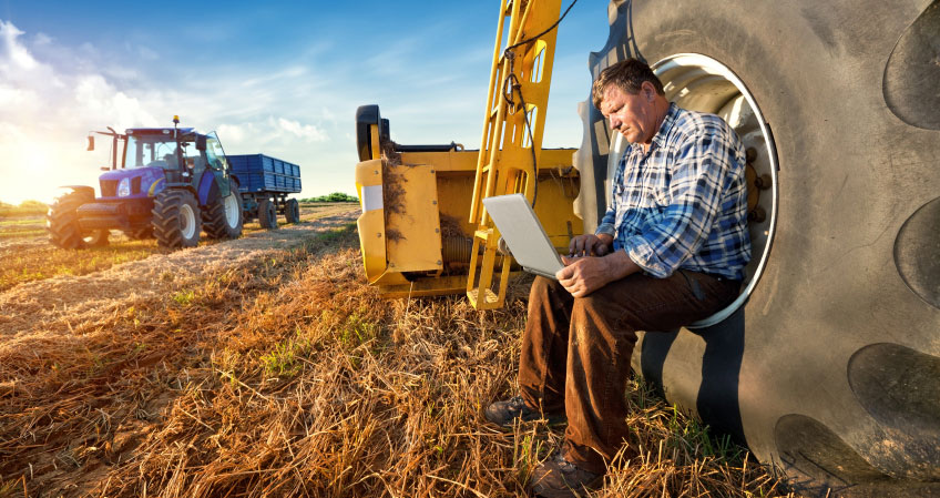 A farmer using a laptop on farm