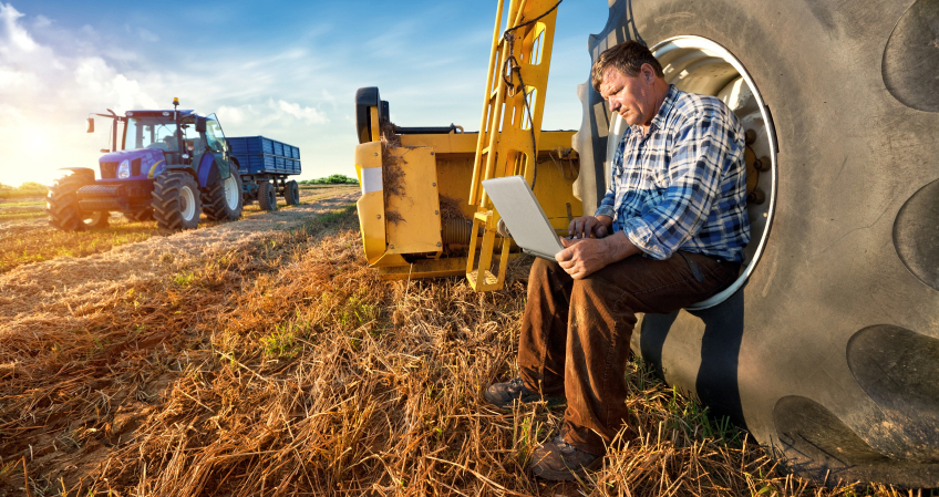 A farmer using a laptop on farm