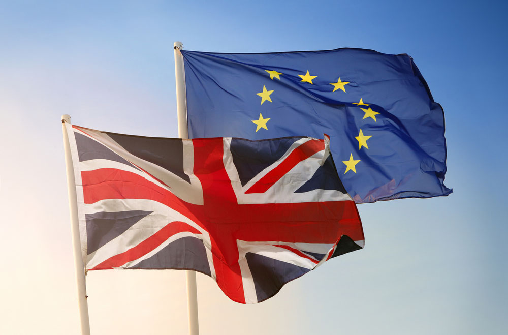 EU and UK flags flutter against a pale blue sky