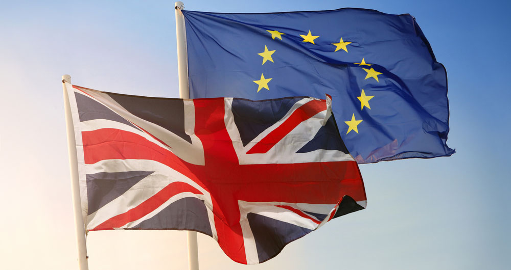 EU and UK flags flutter against a pale blue sky