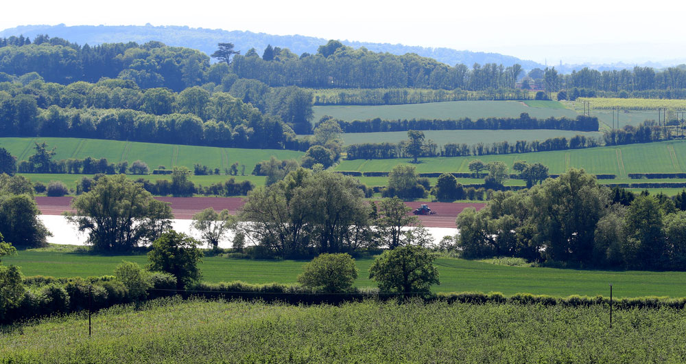 A Herefordshire farming landscape with a distant tractor working the land