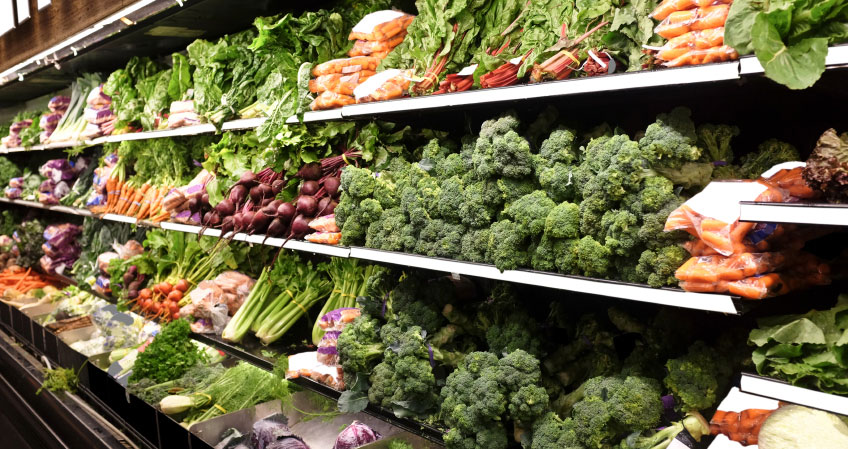 A photograph of vegetables on a supermarket shelf