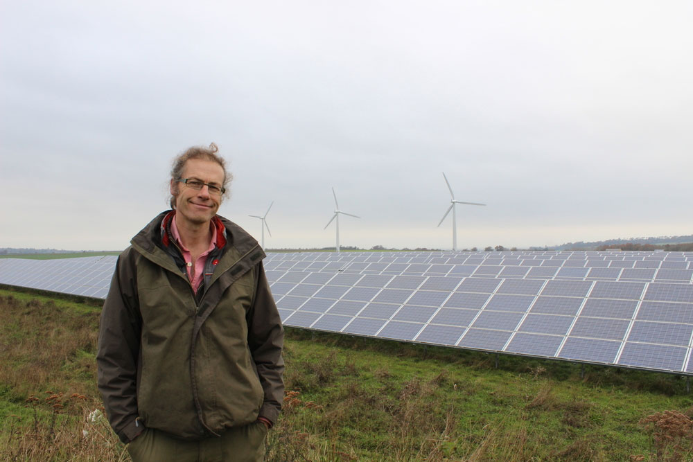 An image of NFU member Adam Twine pictured in front of solar panels on farm