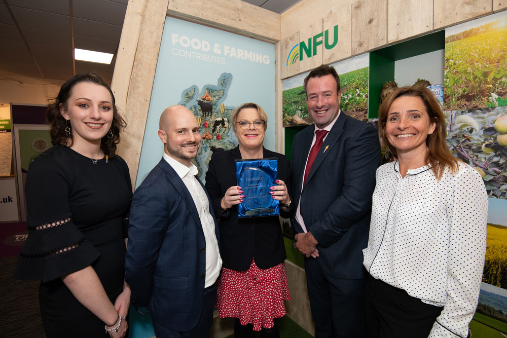 Eddie Izzard pictured presenting the award to NFU Vice President Stuart Roberts, director of communications Fran Barnes and external affairs colleagues Rocky Lorusso and Emma Crosby.