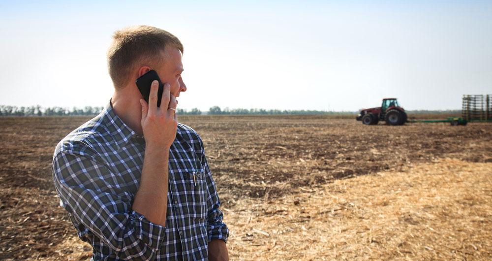 man on phone in field with tractor