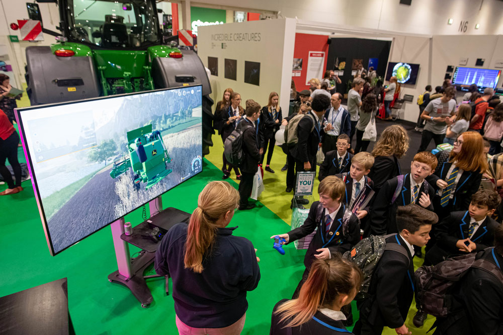 Georgina Barratt, NFU Student and Young Farmer Ambassador, talks schoolchildren through the farming simulator at the Future of Farming exhibit at New Scientist Live, Excel, 10 October 2019