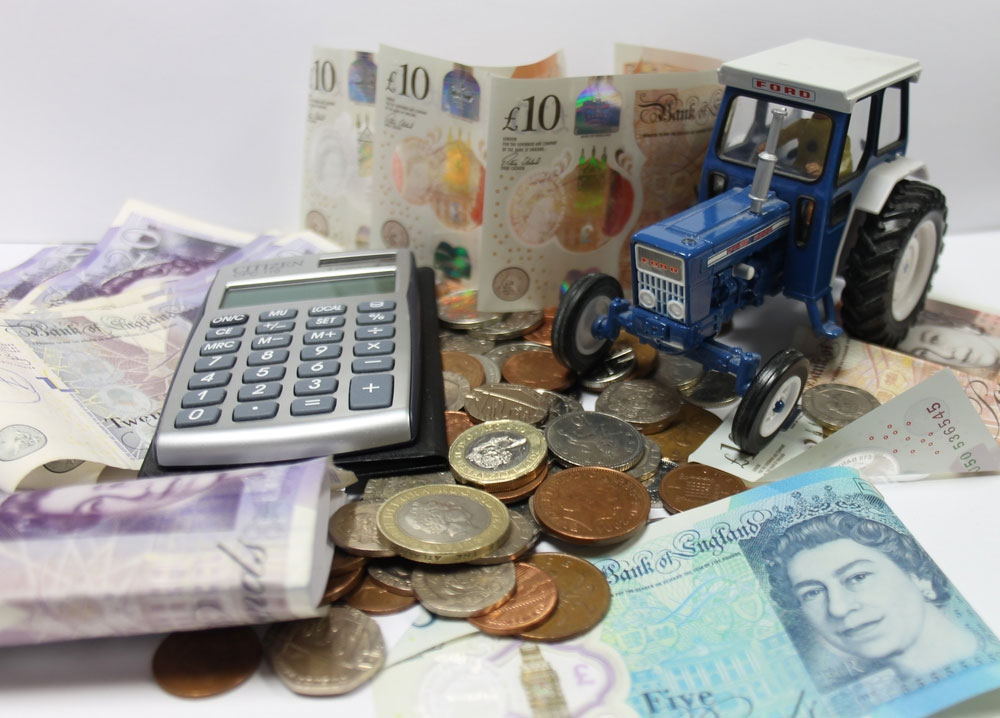 A pile of cash with a miniature tractor and calculator