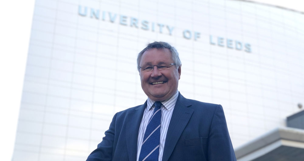 Tim Bennet standing with large, glass fronted University of Leeds building behind