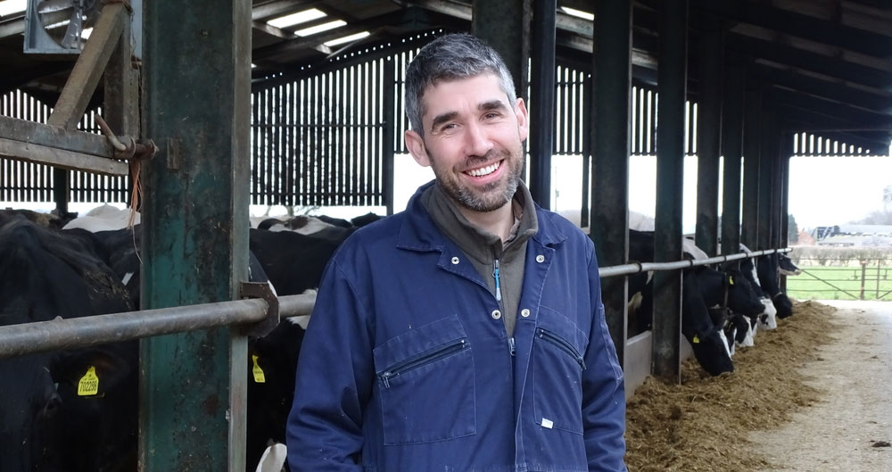 Paul Tompkins on his farm, standing in front of his dairy cows